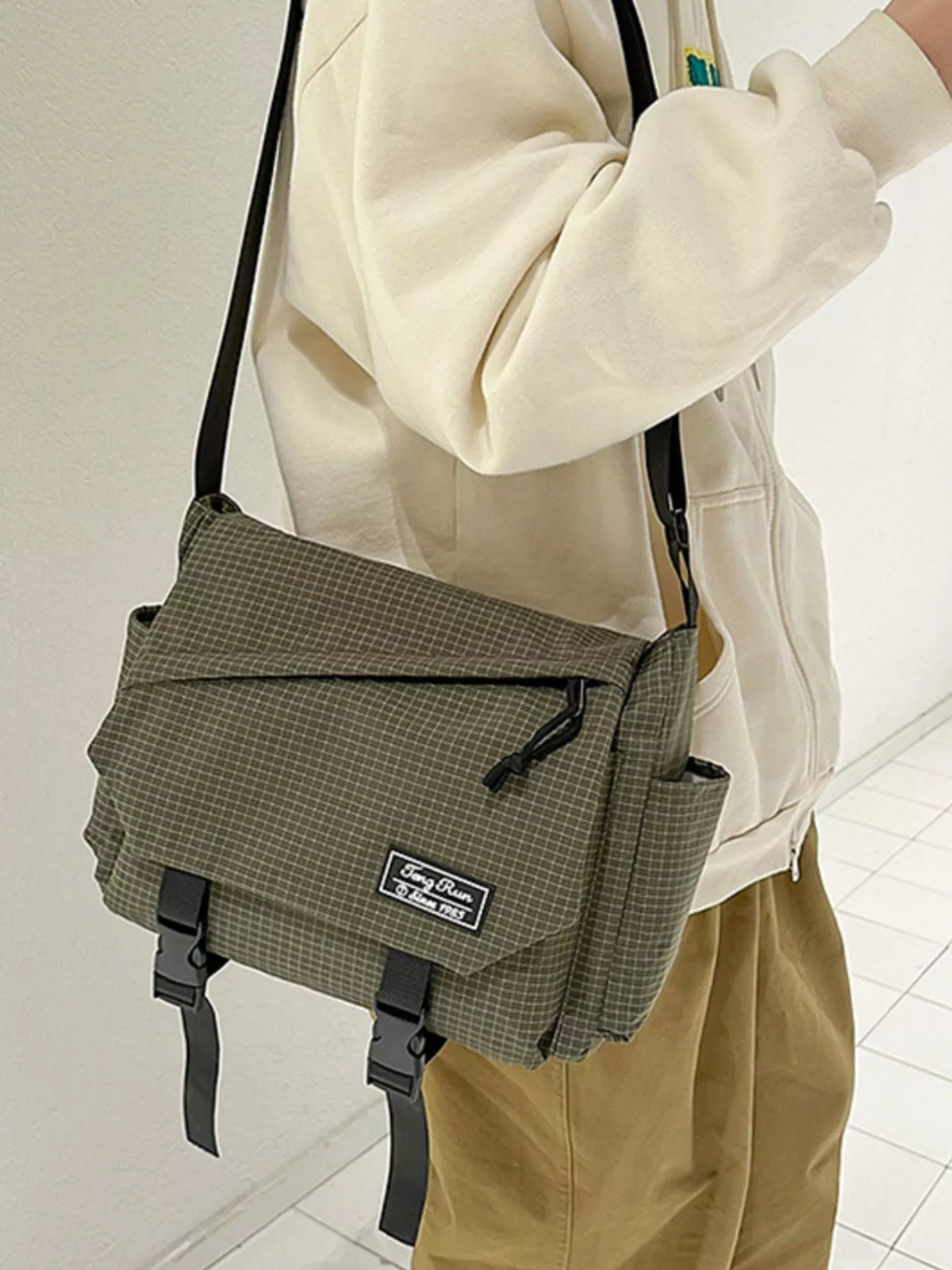 Olive checked crossbody messenger bag worn at the hip with a cream sweatshirt