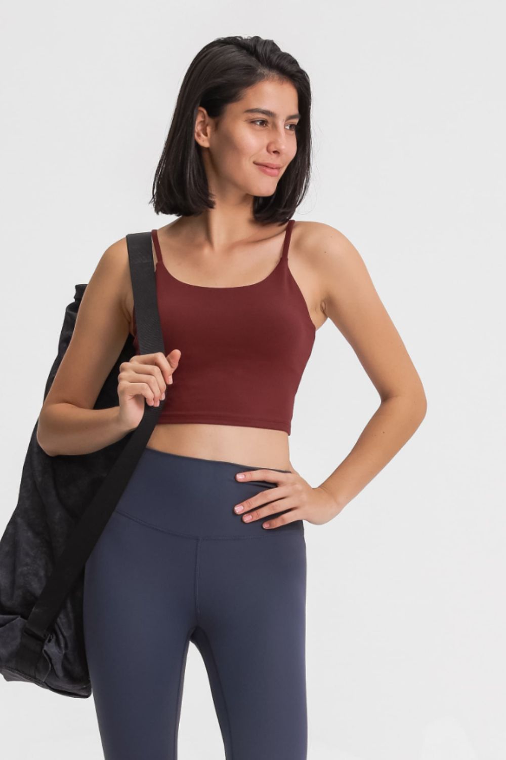Model wearing a burgundy cami and navy leggings, carrying a black shoulder bag.