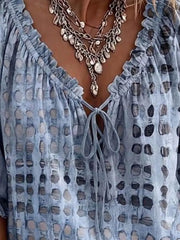 Close-up of the light blue blouse's ruffled V-neckline and ties.