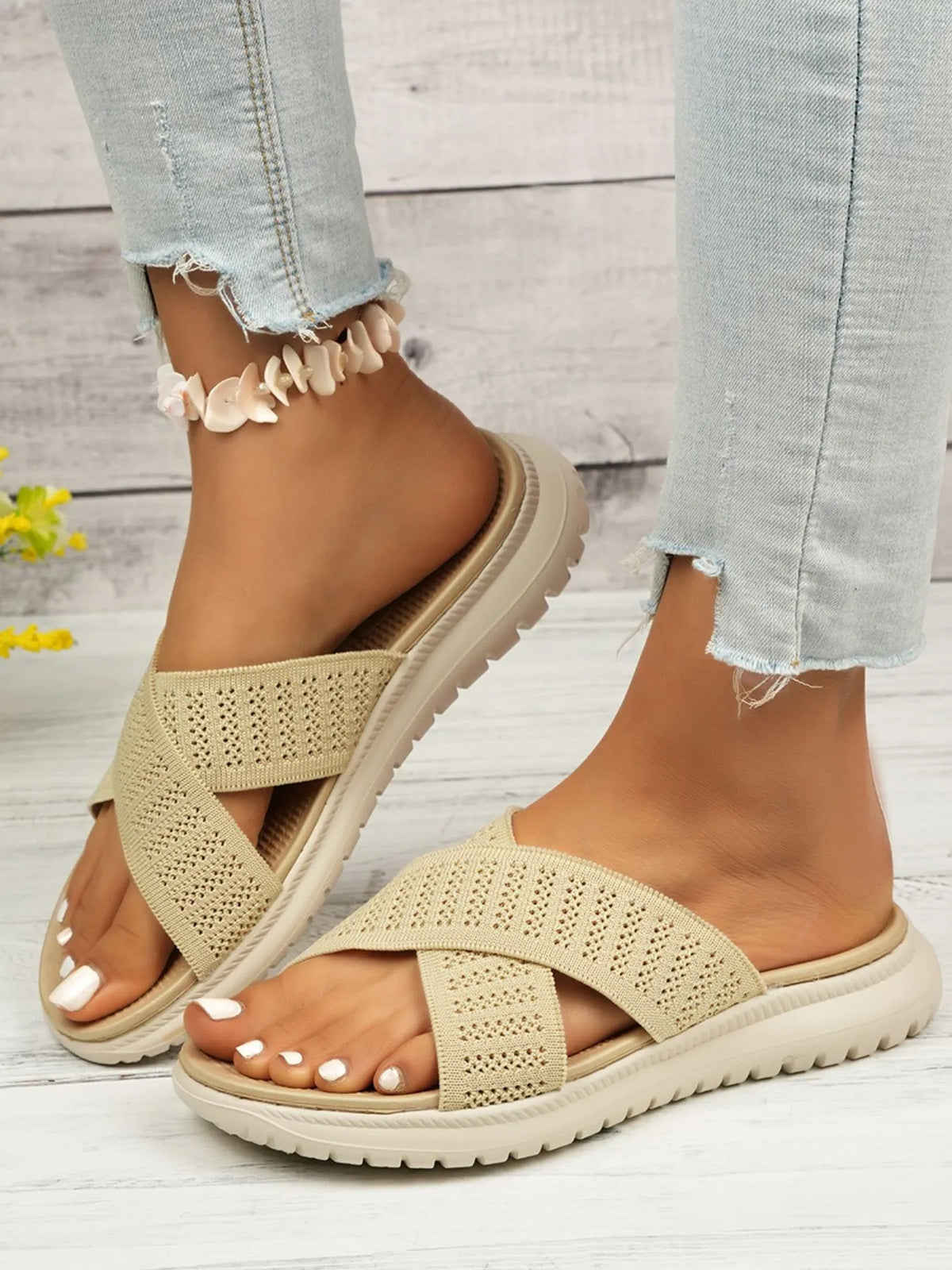 Beige cross-strap slides shown from the side with open toes and pale treaded soles
