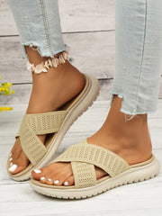 Beige cross-strap slides shown from the side with open toes and pale treaded soles