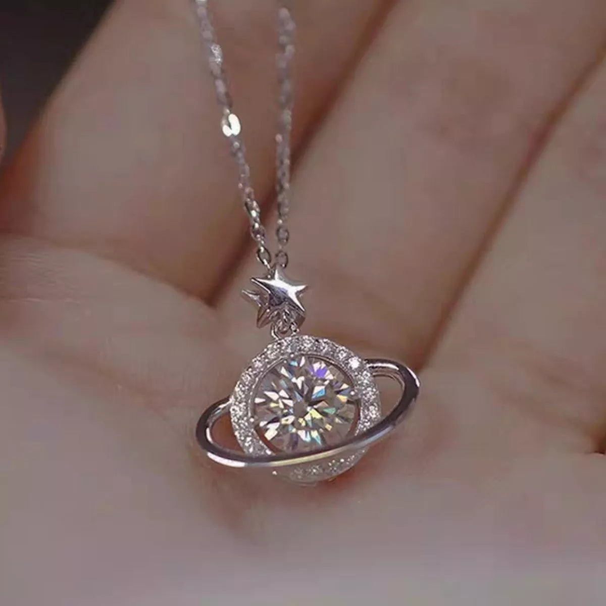Close-up of round moissanite planet pendant with orbit ring and star detail