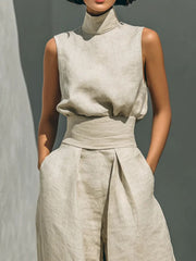 Closer front view highlighting the sleeveless turtleneck and high-waisted trousers.