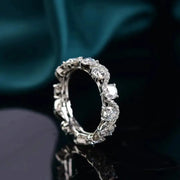 Angled close-up of the ornate moissanite band against dark teal fabric.