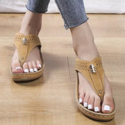 Tan toe-post wedge sandals worn with jeans, front view