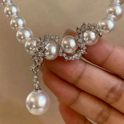 Hand-held detail of clustered zircon centerpiece and dangling pearl on necklace