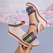 Beige embroidered wedge sandals shown from the side with ankle straps