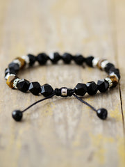 Close-up of black faceted beads, brown accents and adjustable cord ends on a bracelet