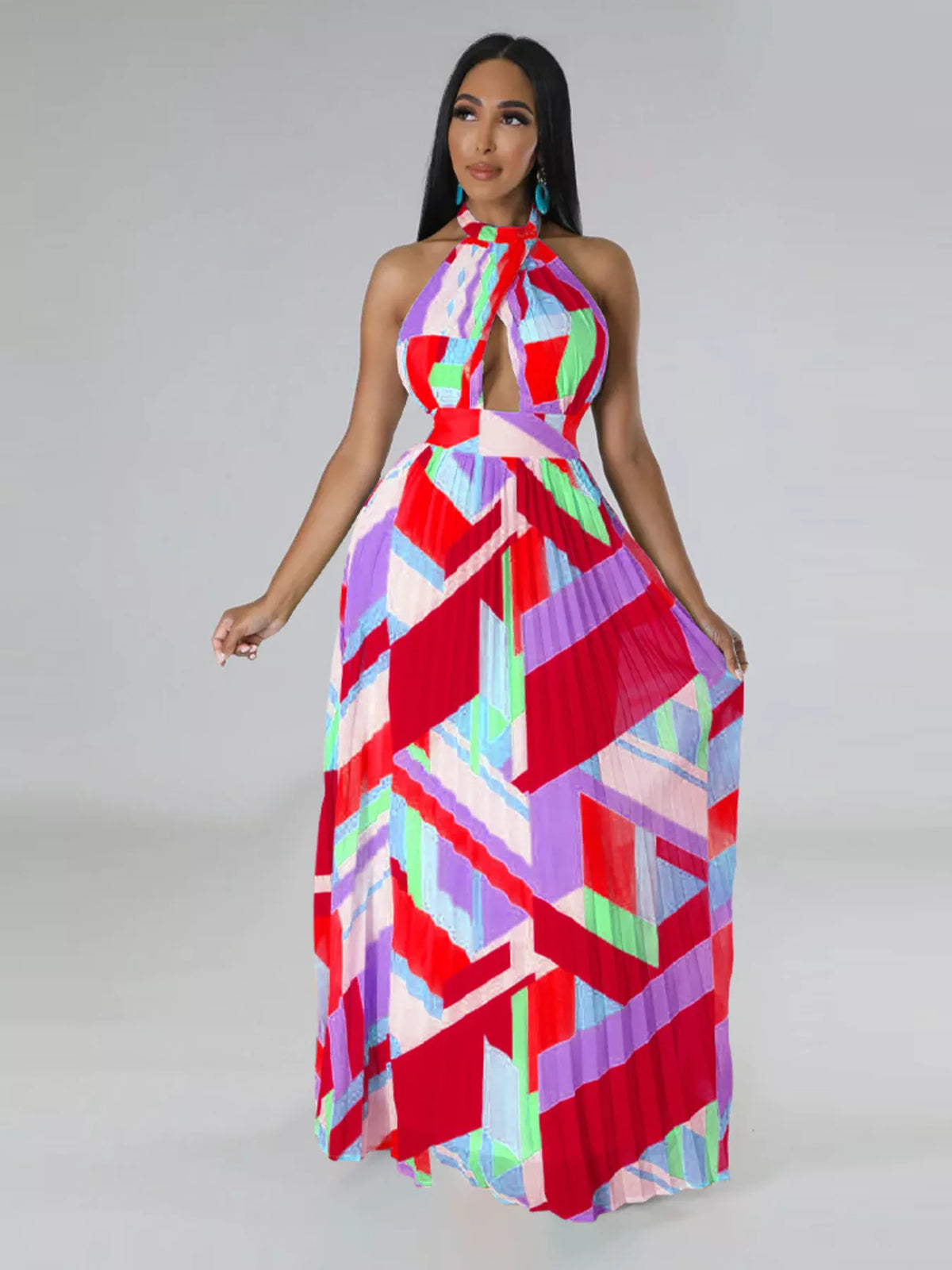 Red and pink geometric maxi dress on a model holding both sides of the pleated skirt.