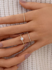 Gold-tone solitaire ring worn with delicate silver stacking rings