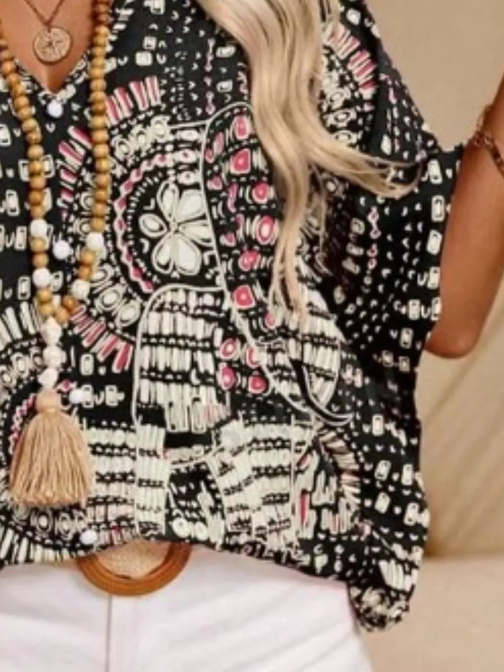 Close-up of the black-and-white blouse showing medallion motifs, V-neck and tassel ties.