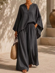 Woman in a charcoal notched-neck top and wide-leg pants, full-length view.