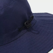 Close-up of the navy hat's side cord toggle and stitched brim.