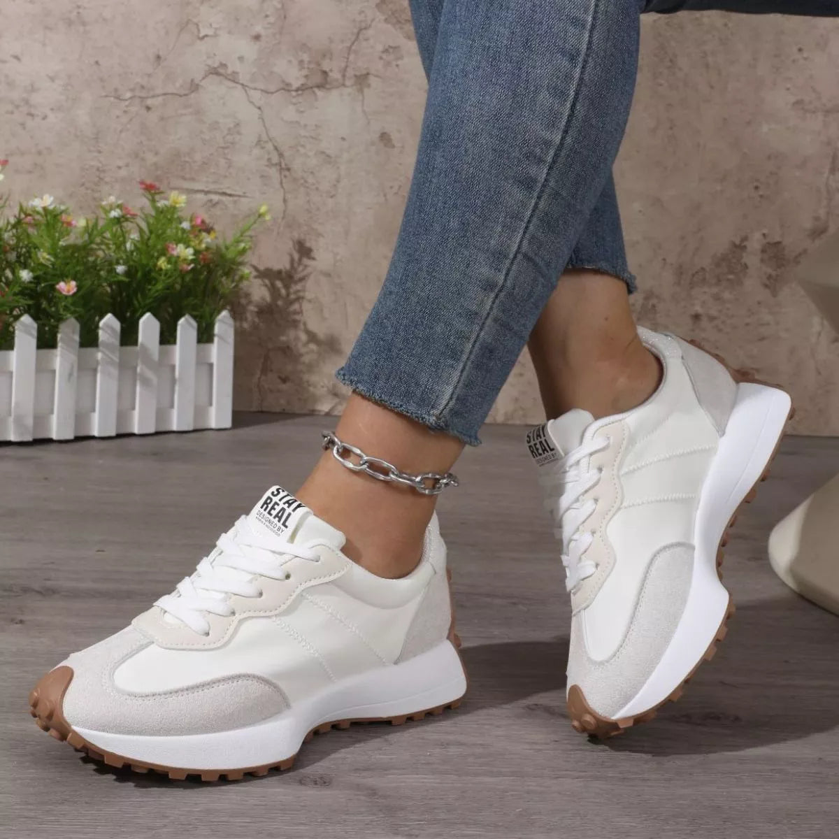 Side view of white and black panel sneakers worn with jeans