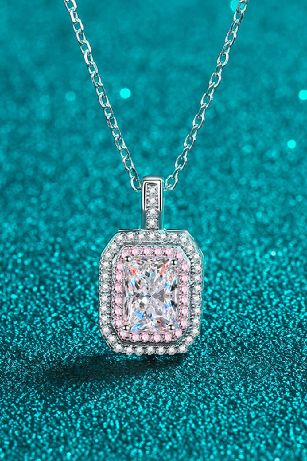 Rectangular clear-stone pendant with rounded corners and pink border on teal