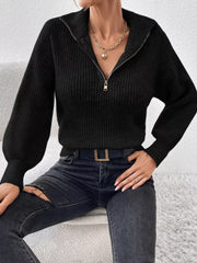 Seated model wearing a black ribbed quarter-zip sweater with open collar