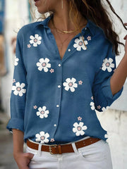Blue button-down shirt with white floral print, worn with white jeans.