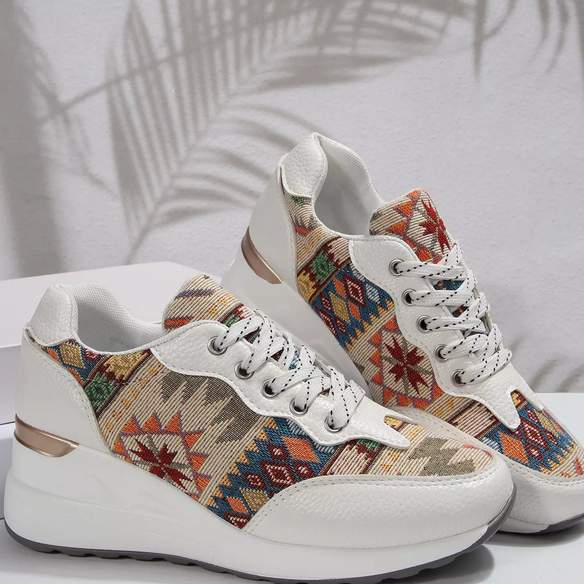 Pair of cream sneakers with multicolor patterned sides displayed on white background