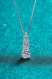 Three-stone pendant necklace displayed against teal fabric