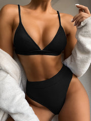Model wearing a black ribbed spaghetti-strap bikini with high-waisted bottoms