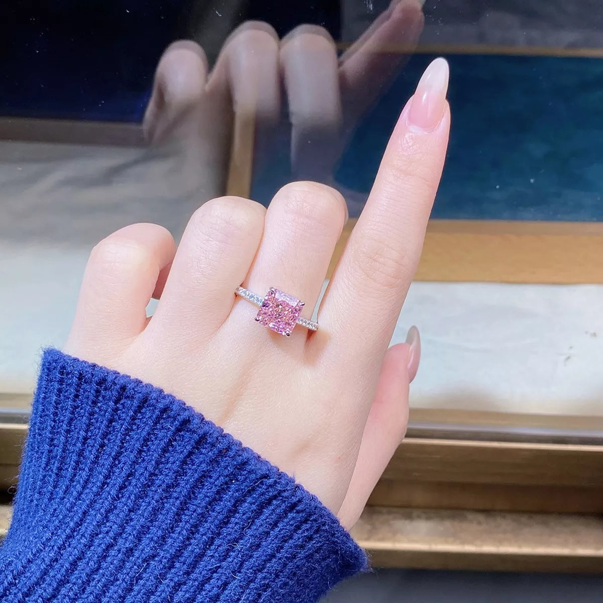 Pink square stone ring held in fingers, angled view