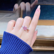 Pink square stone ring held in fingers, angled view