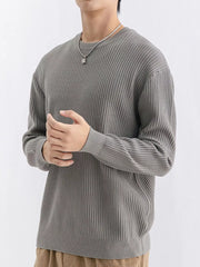 Angled view of medium grey crew-neck sweater with the model's hands held together