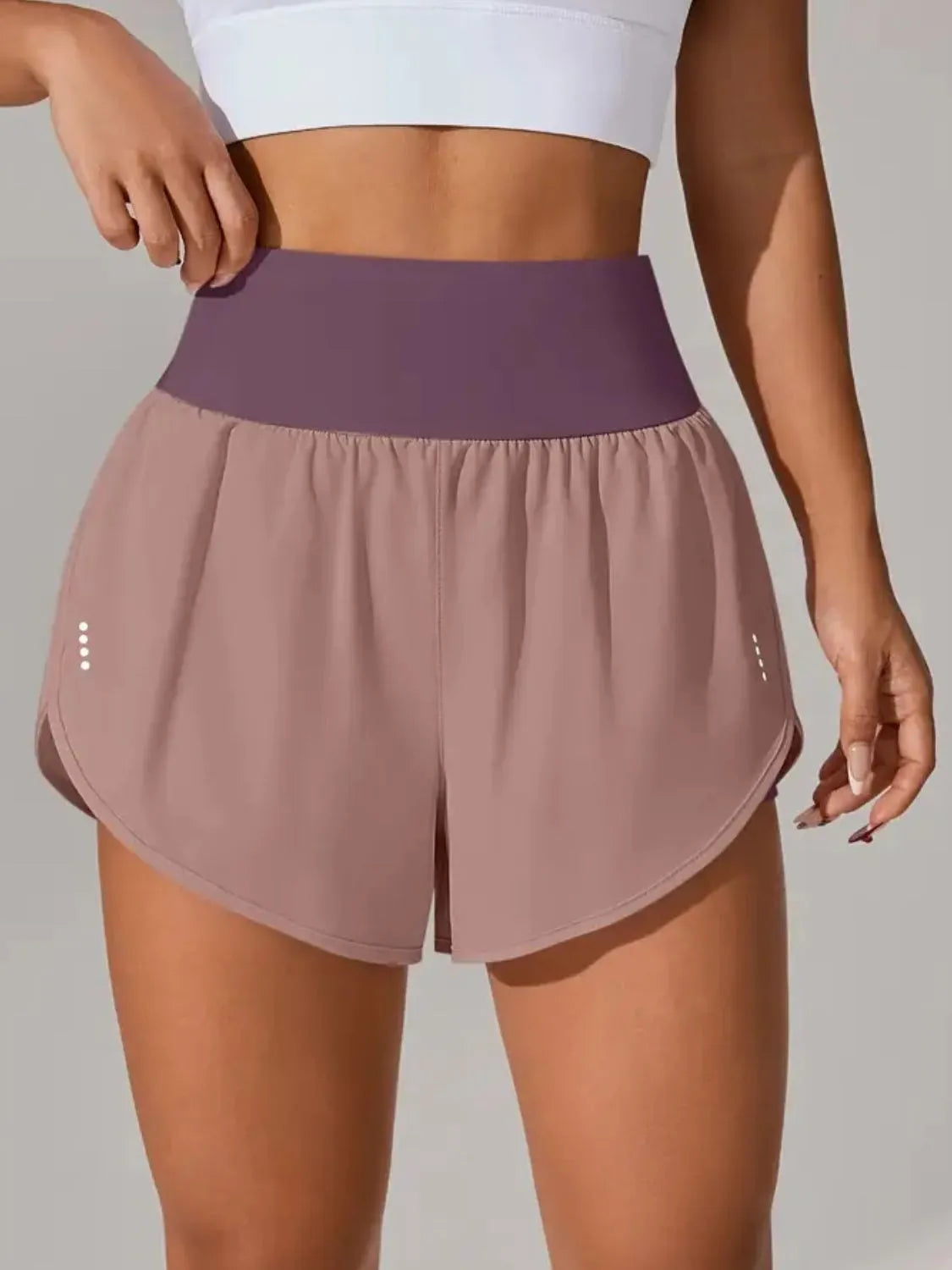 Taupe-pink running shorts with contrasting purple waistband, front view