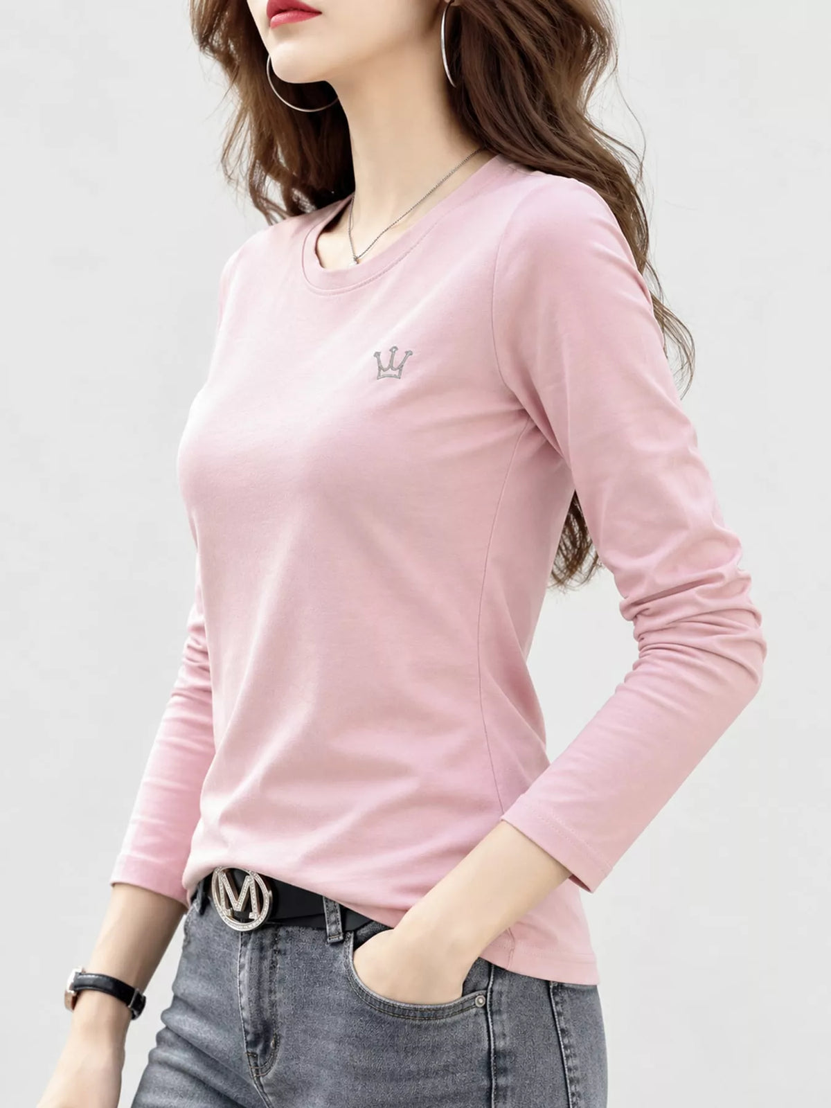 Pink long-sleeve crewneck T-shirt on a model, viewed from the front at an angle.