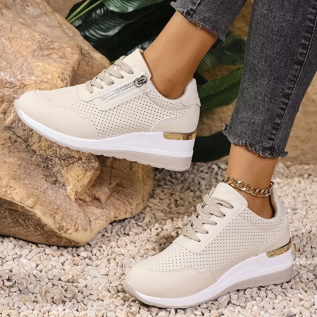 Cream knit lace-up sneakers with white wedge soles worn beside rocks