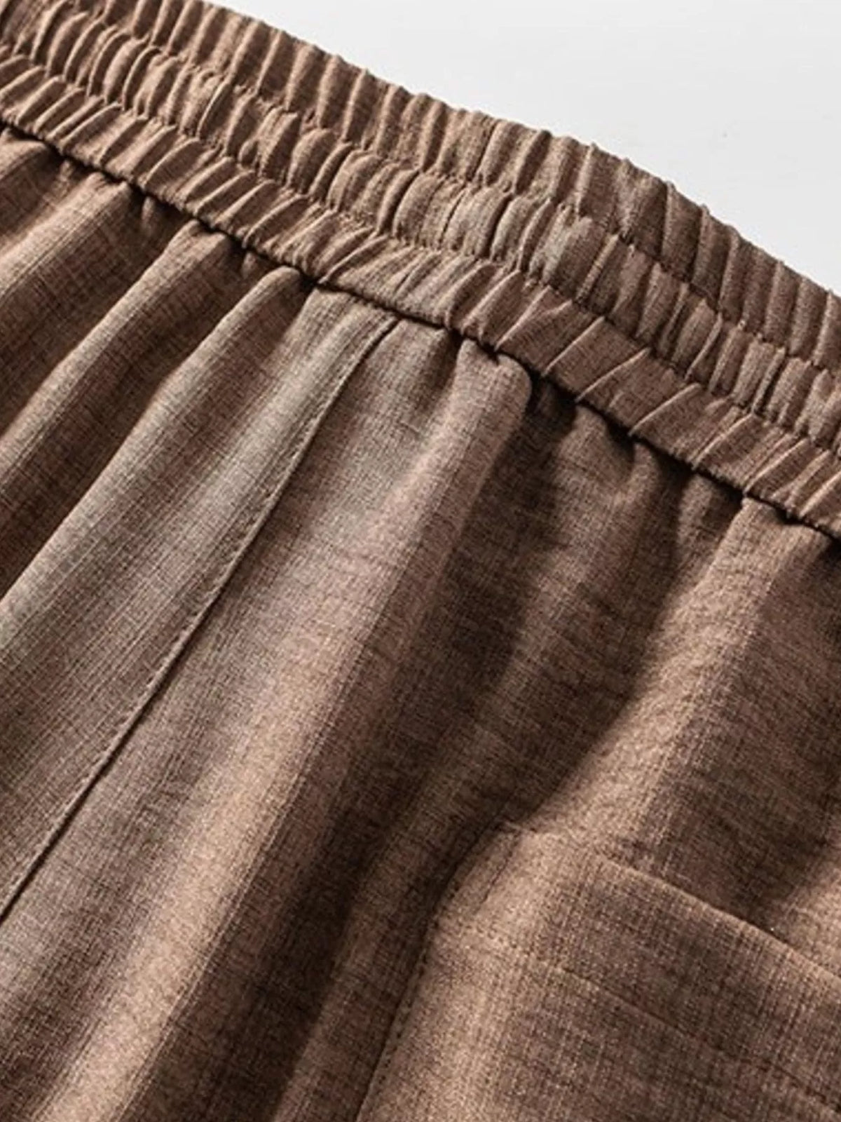 Close-up of the brown shorts elastic waistband and gathered fabric.