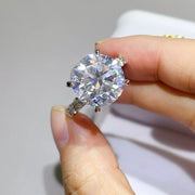 Front view of clear round-stone moissanite ring held between fingers