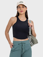 Model wears black racerback cropped tank with cap and teal joggers