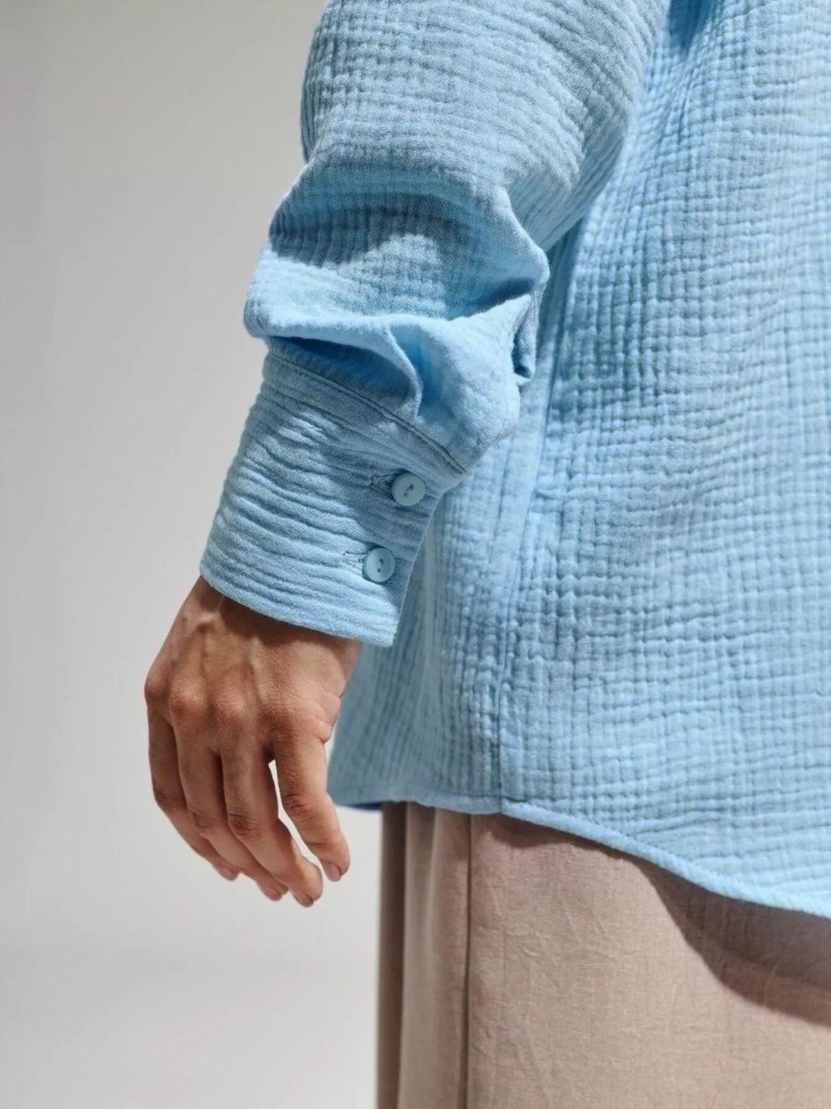 Close-up of the blue shirt sleeve showing its crinkled gauze texture.