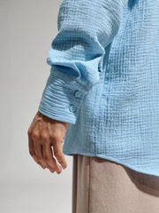 Close-up of the blue shirt sleeve showing its crinkled gauze texture.