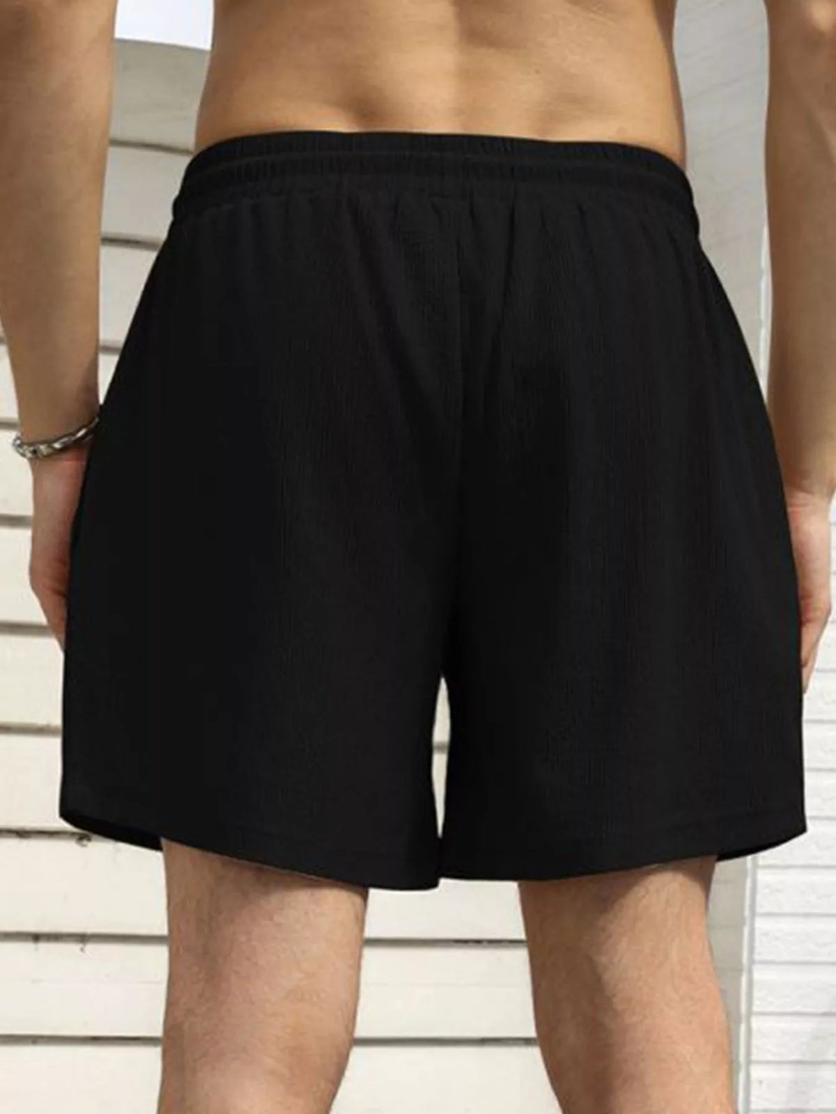 Model wearing black drawstring shorts, back view