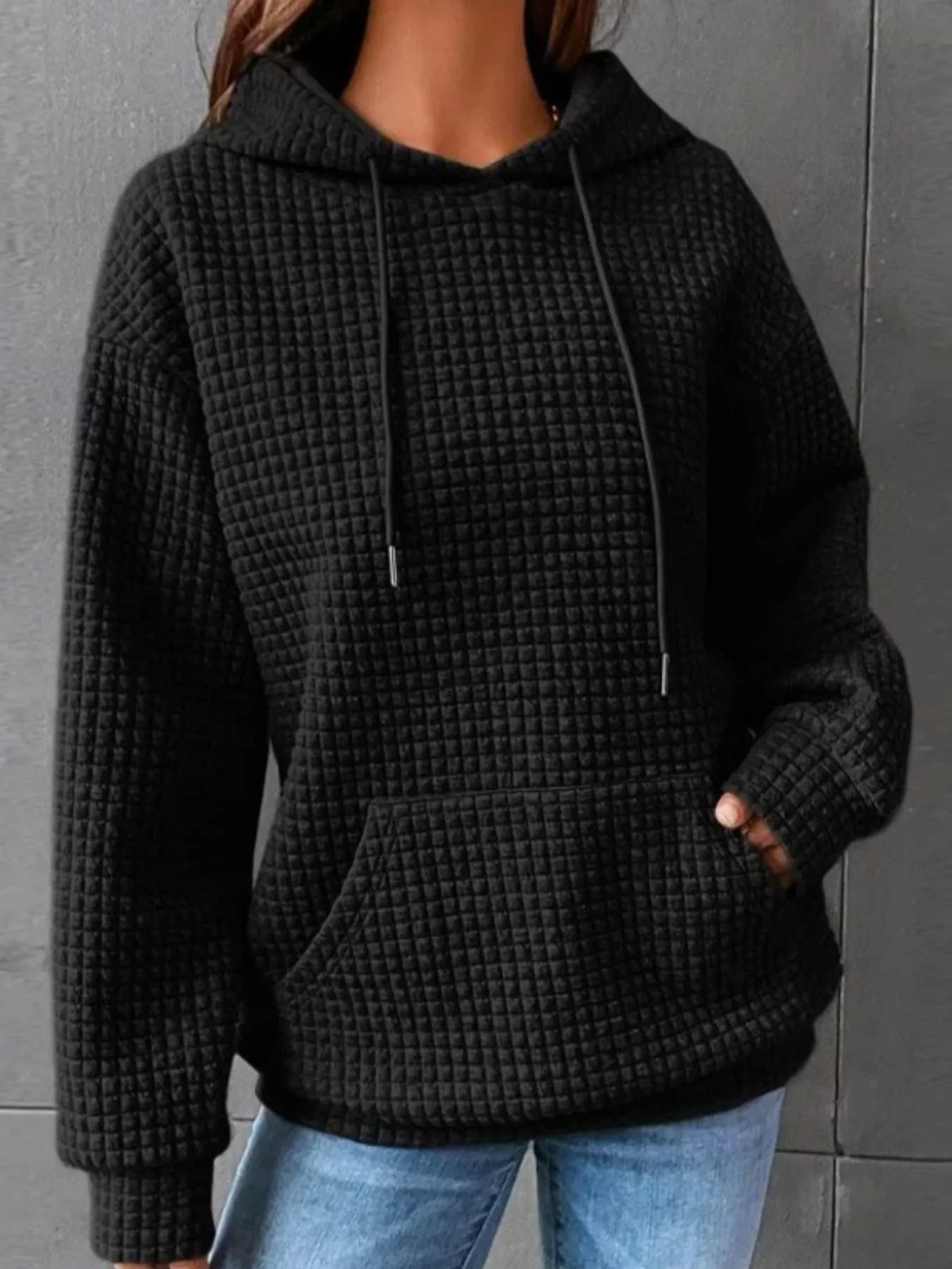 Black textured kangaroo-pocket hoodie worn with jeans