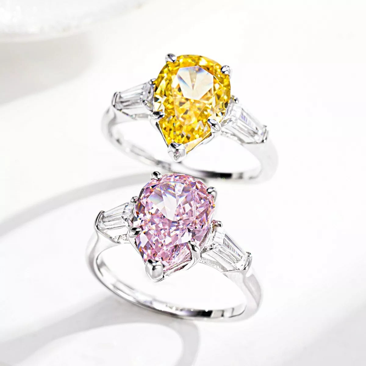 Silver-tone ring with a yellow pear-shaped center stone and clear side stones.