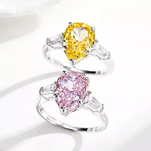 Silver-tone ring with a yellow pear-shaped center stone and clear side stones.