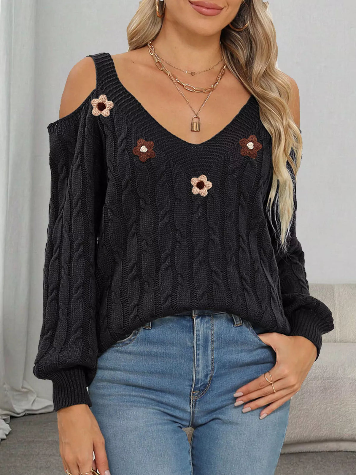 Black cable-knit sweater with floral appliqués, V-neck and cold-shoulder openings, front view