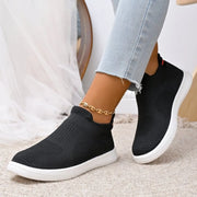 Black knit slip-on shoes with white soles and sock-style collars, front angled view on feet