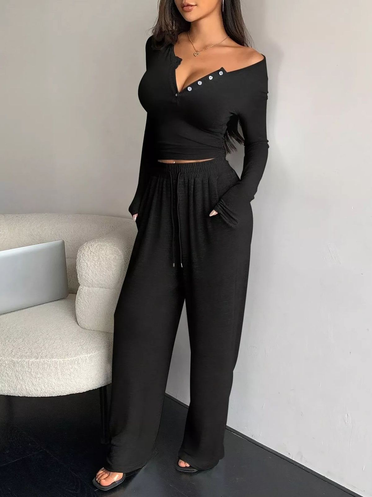 Model wearing black button-detail long-sleeve top with wide-leg pants
