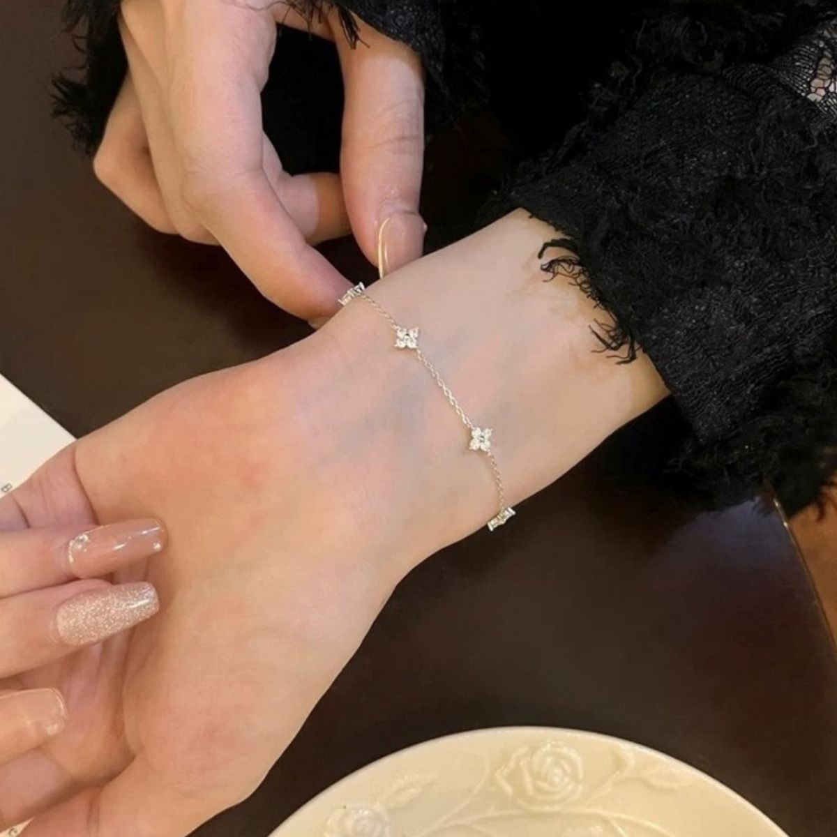 Close view of silver clover bracelet on wrist with dark sleeve