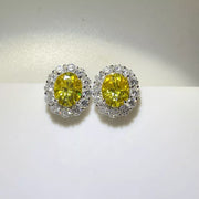 Pair of yellow oval moissanite stud earrings with clear halo stones.