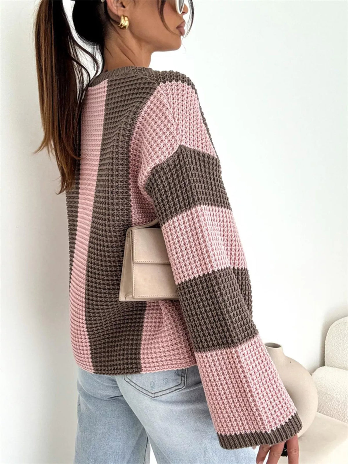 Side view of pink and brown colour-block sweater showing striped sleeve