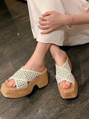 Cream cross-strap platform sandals with open toes shown on crossed feet