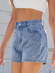 Angled view of blue denim shorts showing studded front panels and plain side seams