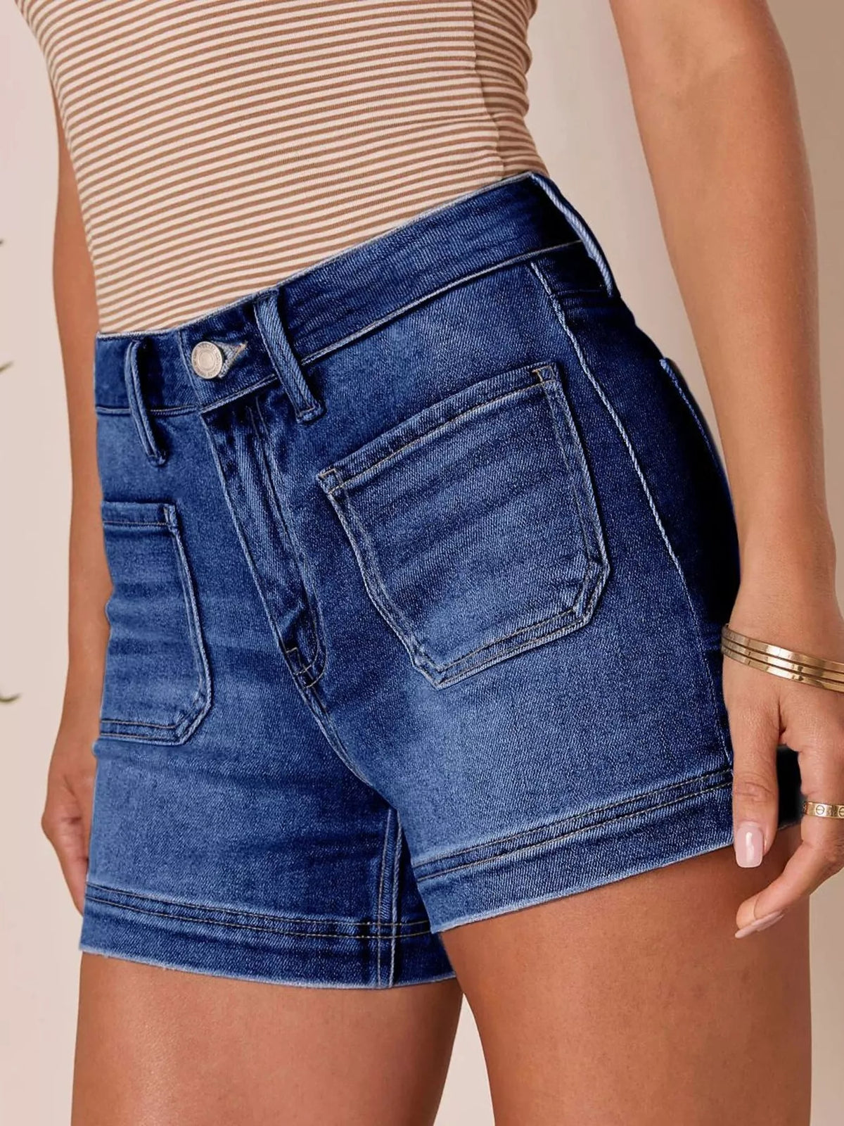 Dark indigo high-waisted denim shorts with front pockets, modeled at a side angle.