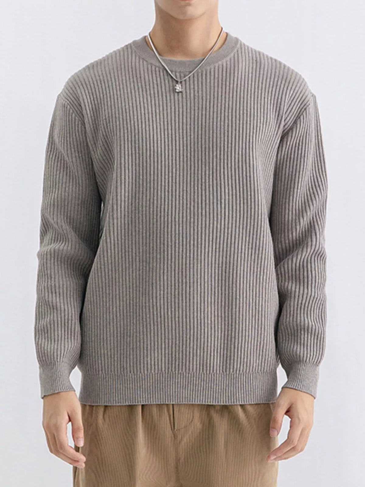 Model facing forward in a taupe ribbed crew-neck sweater and tan trousers