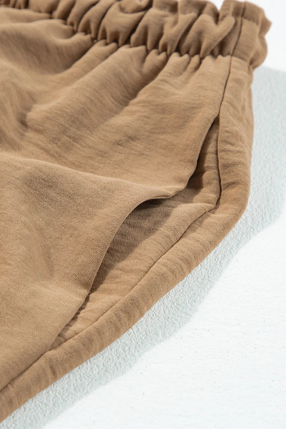 Close-up of the elastic drawstring waistband on tan utility trousers